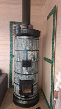 A Siberia green serpentine masonry heater featuring custom matching green stone trim on the wall behind the unit.