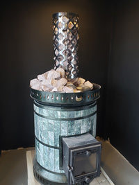 Green serpentine sauna heater topped with contrasting white quartz sauna stones