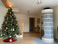 A finished DIY blue Siberia masonry heater kit with grey soapstone cladding installed in a home with wooden floors and holiday decor.