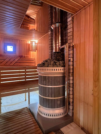 Side view of wood fired blue soapstone sauna masonry eater showing safe installation distances from wooden benches and stainless steel chimney connection